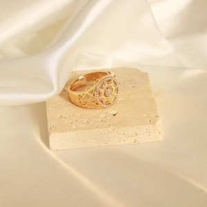 Detail of gold open ring with geometric hollow design and zircon inlay on stone