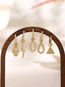 Detail of five gold stainless steel hoop earrings with micro-pave zircon pendants