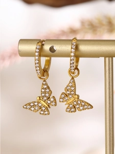 Close-up of gold butterfly earrings with zircon inlay on a display stand