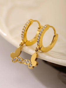 Λεπτομέρεια macro από επίχρυσα σκουλαρίκια 18k με πεταλούδες ζιργκόν σε κεραμικό πιάτο