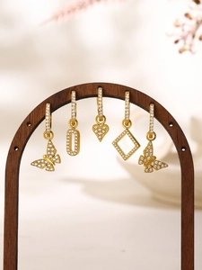 Detailed close-up of five gold huggie earrings with butterfly and heart zircon charms