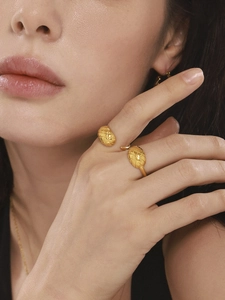 Détail de la bague ouverte dorée avec motif gravé et parure de bijoux sur un mannequin
