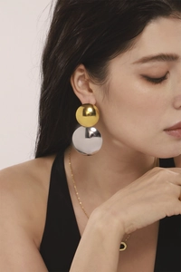 Gros plan sur des boucles d'oreilles géométriques bicolores en acier inoxydable sur modèle