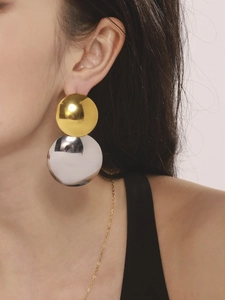 Détail de boucles d'oreilles boules bicolores or et argent sur modèle, style minimaliste