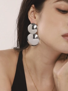 Gros plan sur des boucles d'oreilles pendantes doubles disques argentés polis