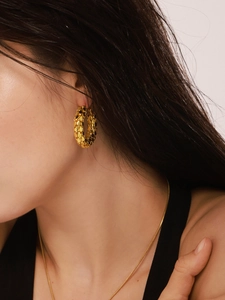 Detail of 18K gold plated hoop earrings featuring a unique scale texture on a model