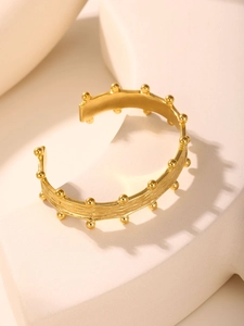Detail showing the brushed 18K gold plated texture and ball beads on the C-shaped bangle