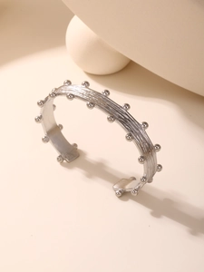 Detail of silver brushed texture cuff bracelet with small bead accents in modern style