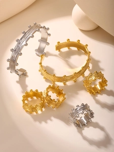 Detailed view of gold and silver plated bangles and rings with brushed texture and metal beads