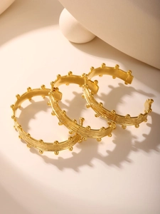 Detail of 18K gold-plated open bangles with ripple texture and bead accents