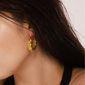 Gold plated 18K stainless steel hoop earrings with scale texture on a model