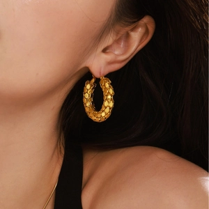 Textured gold hoop earrings with scaly pattern for women shown on model profile
