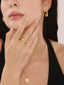 Close-up of gold drip glaze open ring and layered necklace with mother of pearl