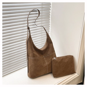 Détail du sac hobo en daim marron avec coutures contrastées et pochette assortie sur fenêtre