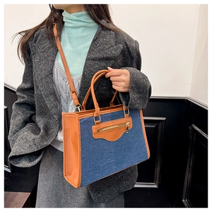 Detalle de las costuras en contraste de denim azul y cuero marrón en el bolso