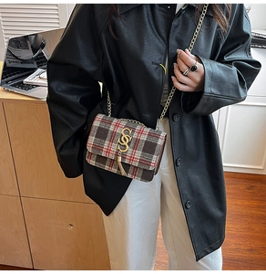 Detail of red and brown plaid crossbody bag with gold metal S-buckle and tassel