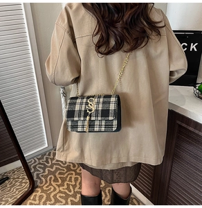 Detailed macro view of black and white checkered crossbody bag with gold chain and tassel