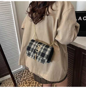 Détail du sac en tweed à carreaux noir et blanc avec logo S doré et gland à franges