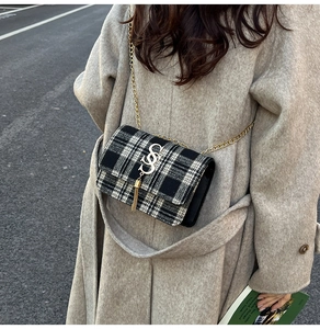 Detail of vintage black and white plaid wool bag with gold S-buckle and tassel