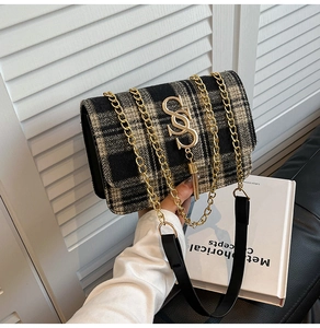 Macro view of tweed checkered handbag with golden logo and decorative tassel detail