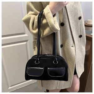 Detail of vintage black suede shoulder bag with dual patent leather front pockets