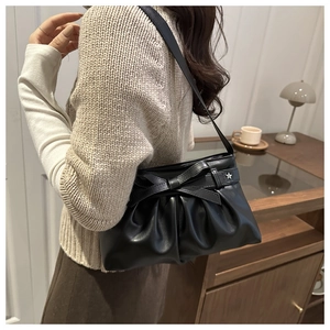 Détail du sac à bandoulière noir plissé avec nœud et étoile sur le mannequin