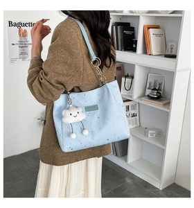 Detail of light blue star print tote bag with plush cloud charm and gold chain strap