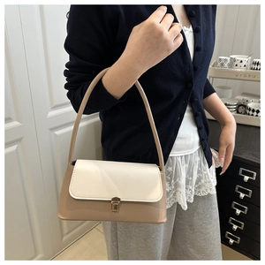 Close-up of contrast color handbag featuring khaki leather and gold metal buckle