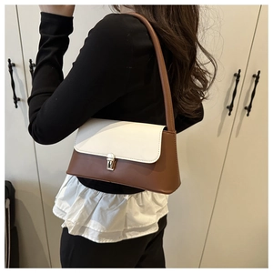 Detail of color-block baguette bag with white flap and gold buckle on model shoulder