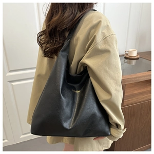 Detail of a large black PU tote bag with gold Fashion text on wide shoulder strap
