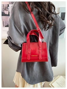 Detail of red wax leather crossbody bag with top handles and fashion text branding