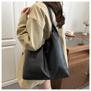 Detail of black pebbled leather tote bag with gold fashion text in a home studio