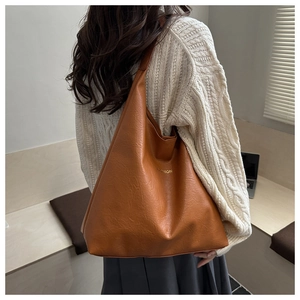 Detail of caramel brown tote bag with fashion text shown on shoulder of a model