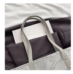 Detail of grey tote bag featuring marble texture, slim leather straps and gold rivets