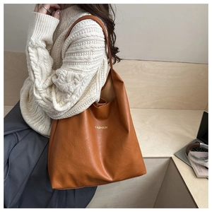 Close-up of cognac large tote bag with gold fashion lettering and smooth PU leather texture