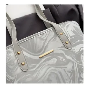 Detail of marble pattern leather texture and golden metal hardware on large tote bag