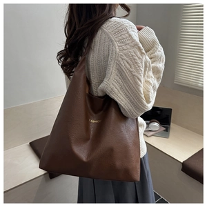 Close-up of brown litchi pattern tote bag with minimalist Fashion text detail