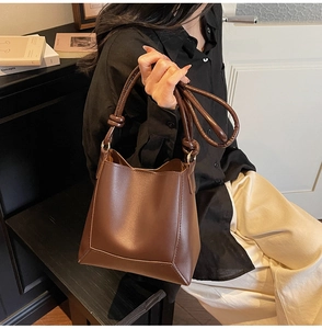 Detail of dark brown leather bucket bag with knotted shoulder strap texture and finish