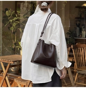 Detail of dark brown bucket bag with structural stitching and knotted shoulder strap