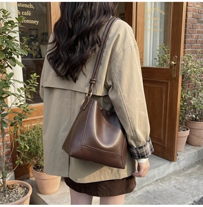Detail of dark brown leather bucket bag with geometric stitching and slim shoulder strap