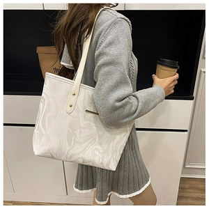 Detail of grey marble texture tote bag with cream straps and gold metal accents