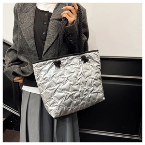 Detailed close-up of metallic silver tote bag featuring star quilting and black rope handles