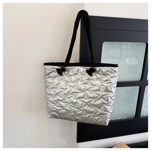 Detailed close-up of silver quilted star pattern with black rope handle on a tote bag