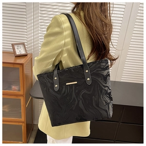 Detail of large black marble pattern tote bag with leather strap on model in suit