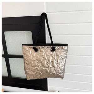 Detail of champagne gold tote bag featuring star quilted texture and woven rope handles
