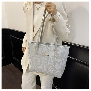 Detail of grey marble pattern tote bag with gold metal plaque and thin shoulder straps