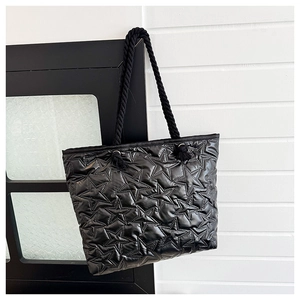 Close-up of star-quilted black nylon tote bag with thick woven rope handles and silver eyelets