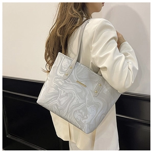 Close-up of a marbled grey tote bag featuring gold hardware and long straps on a model