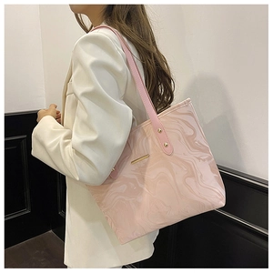 Detail of pink marble pattern tote bag with gold metal trim on white blazer model