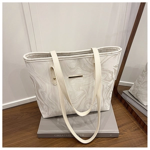 Detail of white marble pattern tote bag with gold metal trim and leather straps
